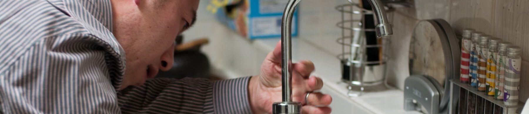 closeup of a plumber from joe cole installing a new sink fixture in a davie florida home