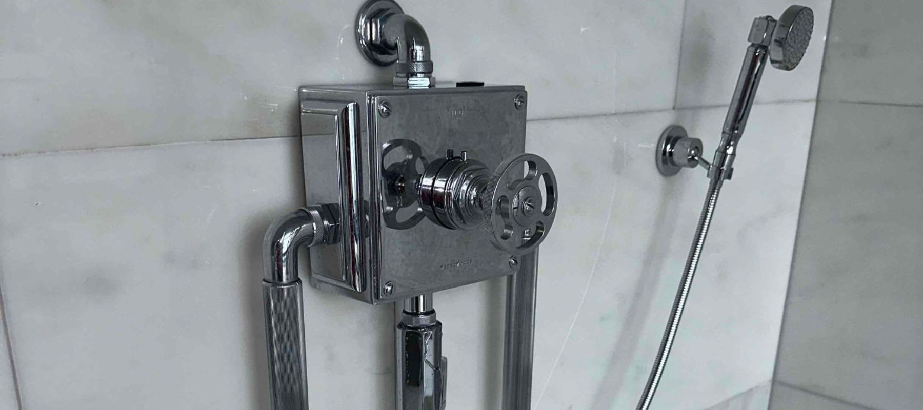 close-up of a modern shower plumbing setup with polished chrome fittings