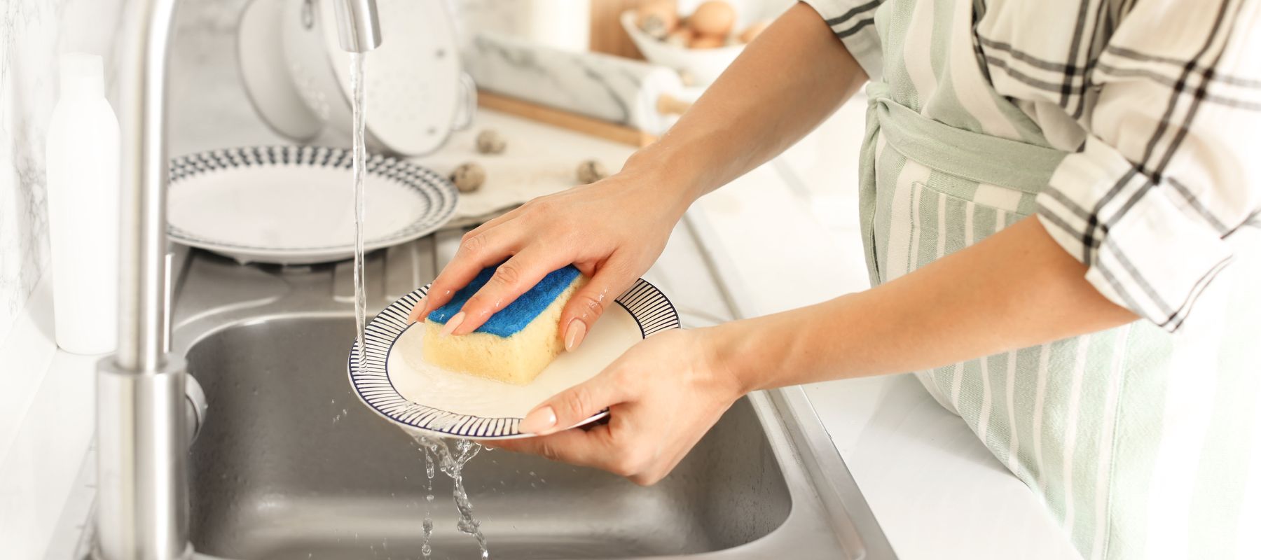 person cleaning dishes over the kitchen sink