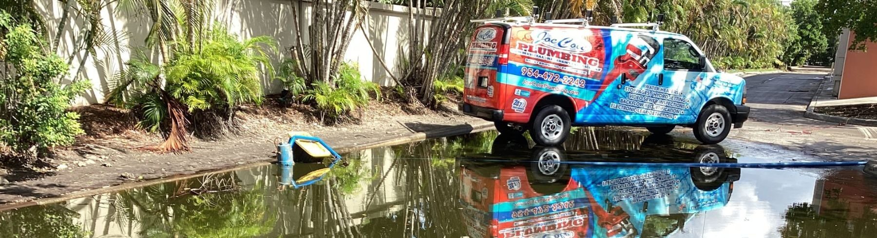 joe Cole Plumbing service van reflected in a waterlogged parking area