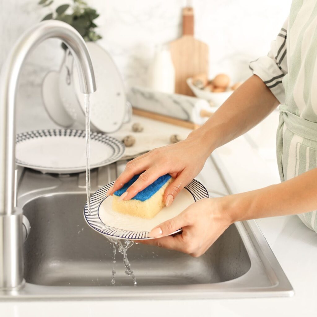 person cleaning dishes in the sink