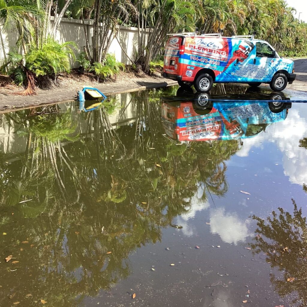 Joe Cole Plumbing service van reflected in a waterlogged parking area