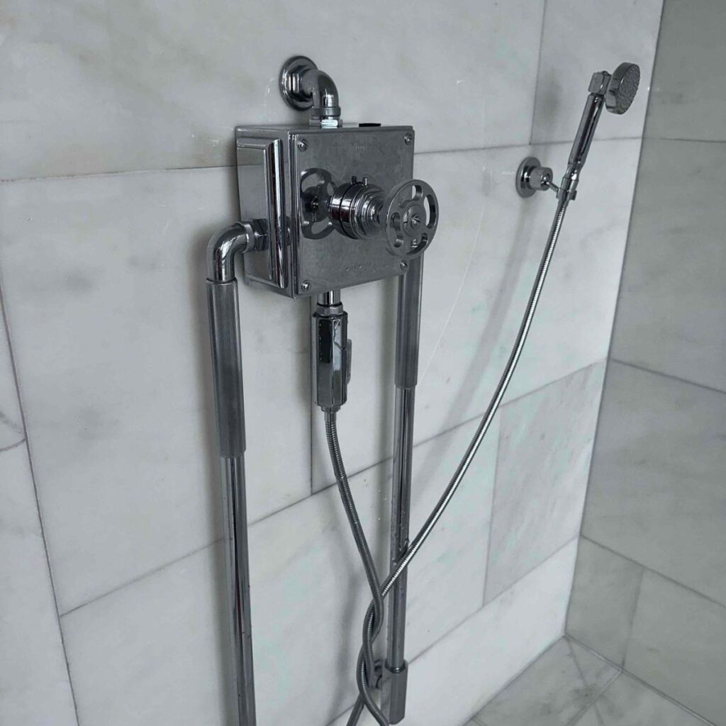 Close-up of a modern shower plumbing setup with polished chrome fittings
