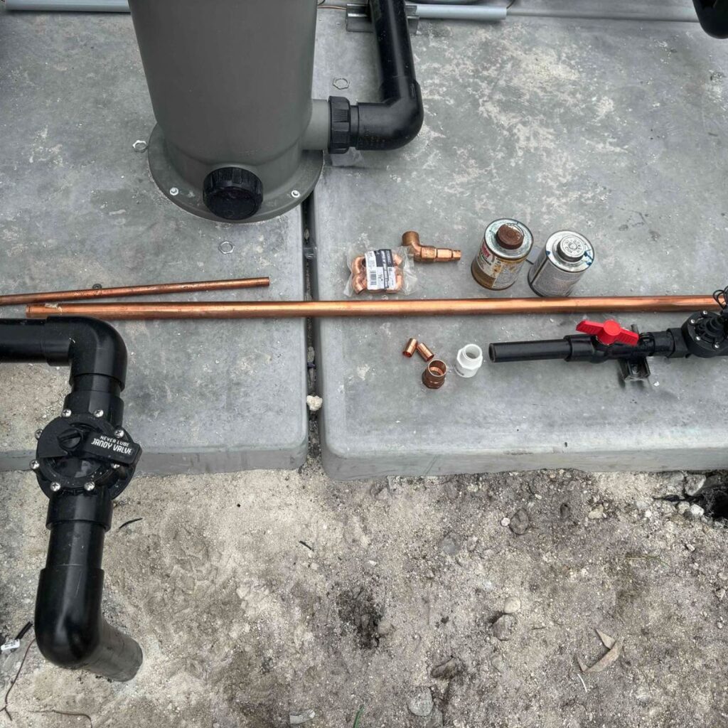 Plumbing tools and copper pipes laid out on a concrete surface for installation