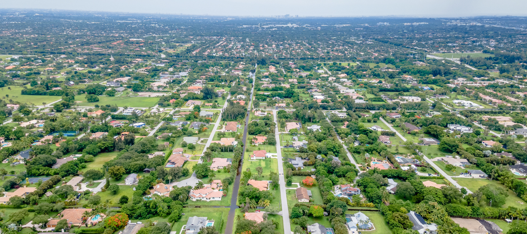An aerial view of a sprawling suburban area with neatly arranged homes surrounded by lush greenery and open spaces