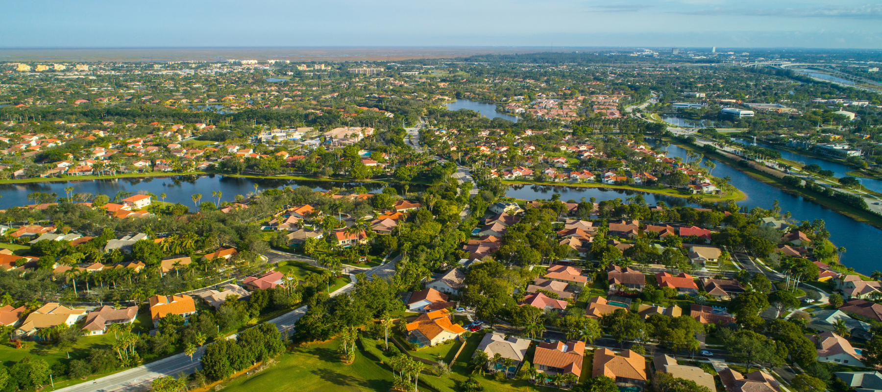 A vibrant aerial view of a suburban neighborhood with winding waterways, colorful houses, and lush landscaping