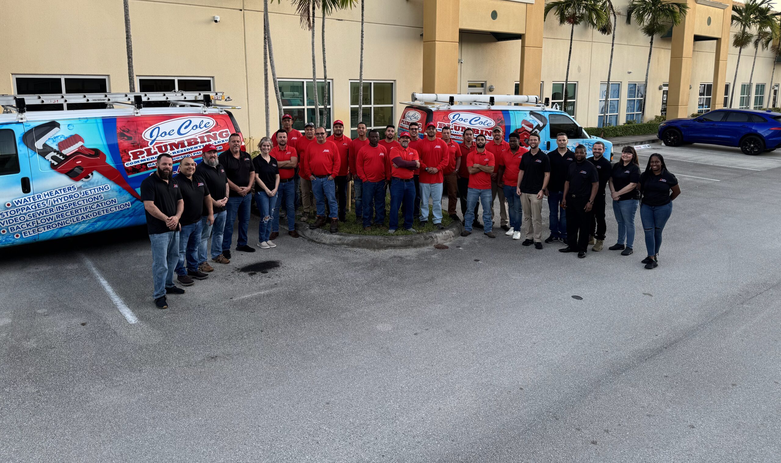 Joe Cole Plumbing team in front of company vehicles outside