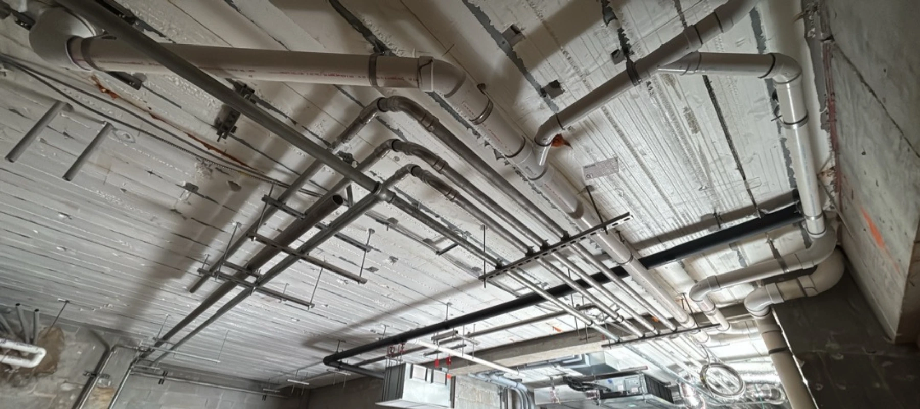 Commercial plumbing system with exposed overhead piping installation in residential building