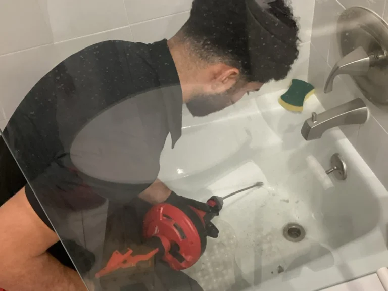 Plumber performing bathroom drain cleaning in a bathtub